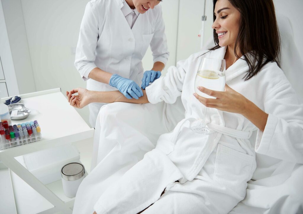 A Woman getting her IV treatments and holding glass with juice | Odomí Medical Spa in Savannah, GA