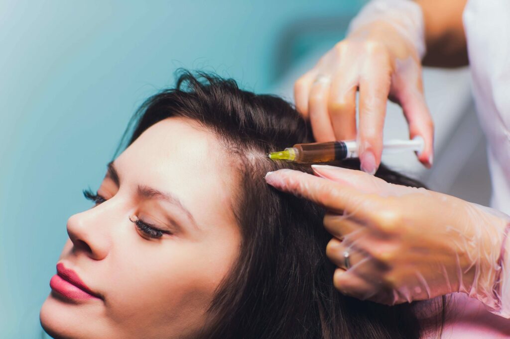 Cosmetologist holding syringe and woman's head in hands Getting Hair Restoration treatment | Odomi Medical Spa in Savannah, GA